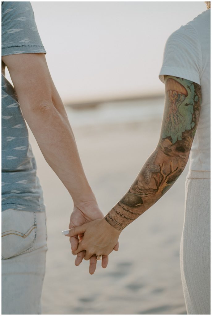 a close up of a couple holding hands with a close up look at the brides tattoo sleeve