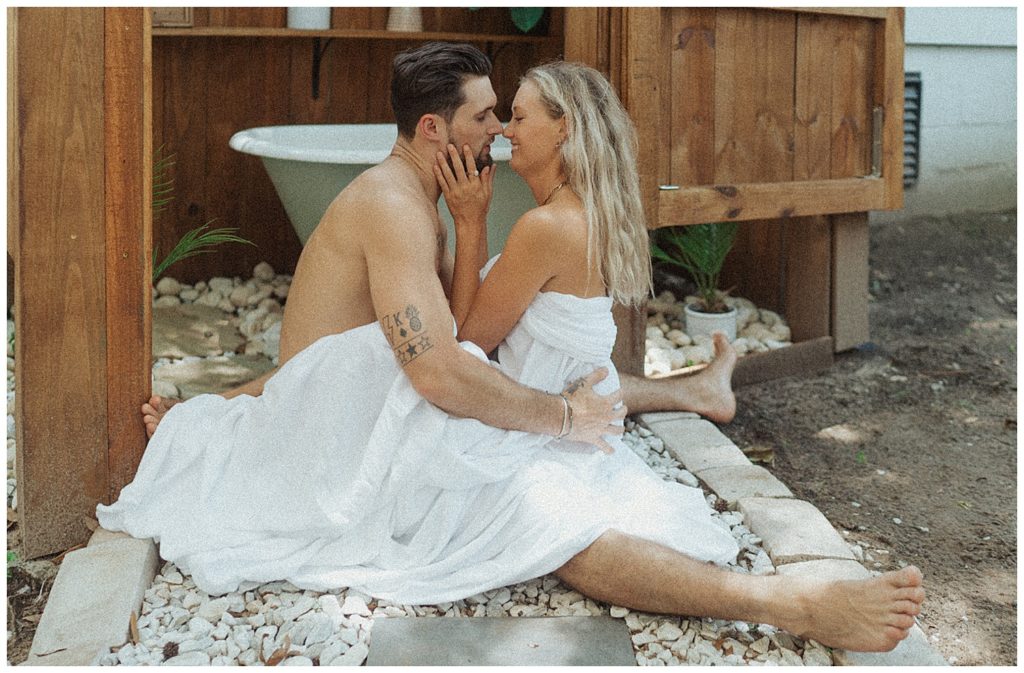 couple laying with each other on the ground looking at each other about to kiss and covered in a white sheet in florida