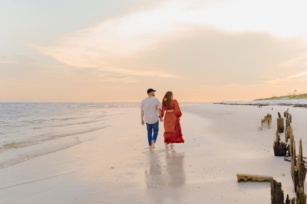 Couple walking and holding hands during couples session at Alligator Point in Florida