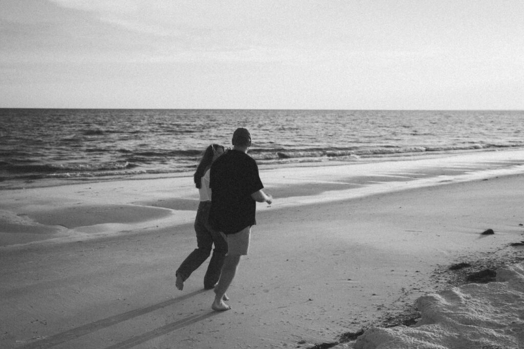 Couple running along the sand during couples session