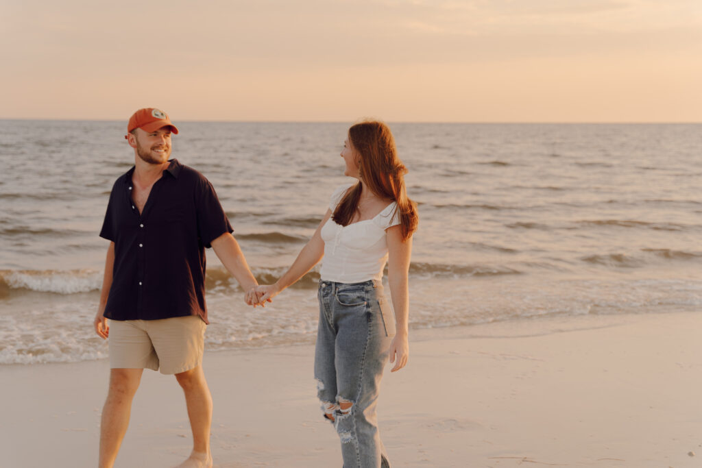 Couple walking along the coast and holding hands during couples session at Alligator Point in Florida