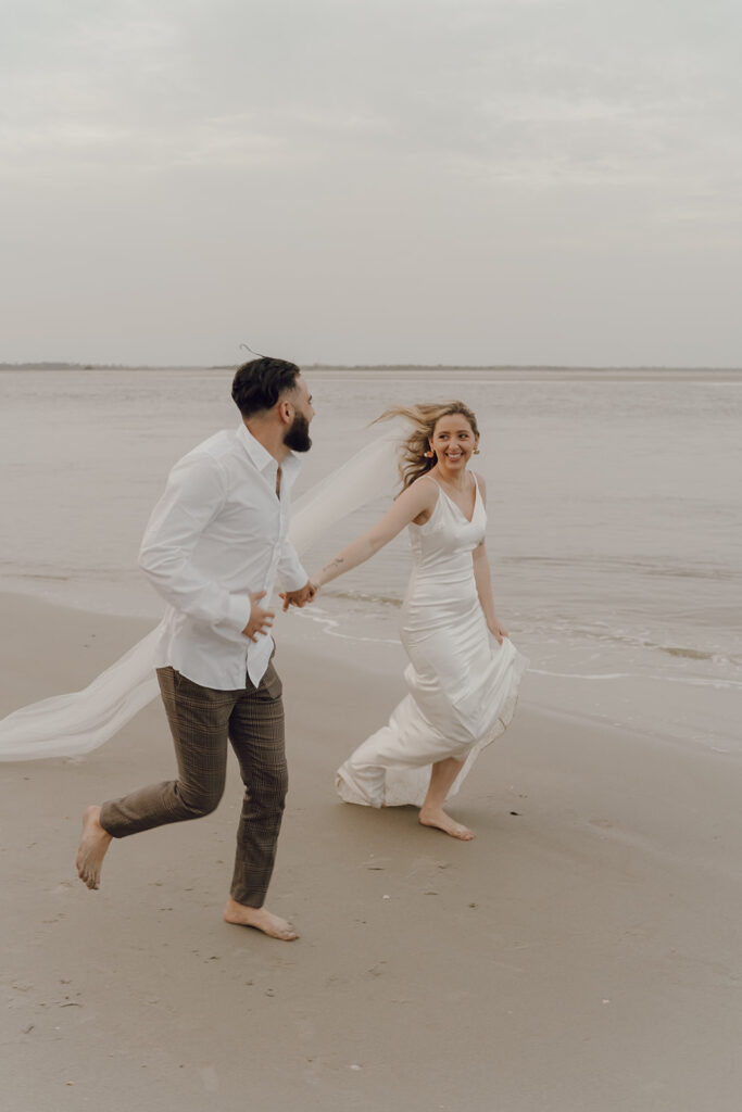 Couple running by the sea at Beach elopement at Folly Beach South Carolina