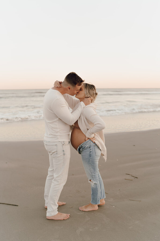Couple kissing on the during maternity shoot