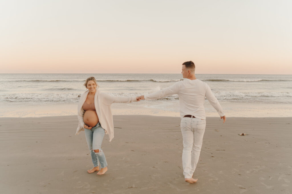 Couple dancing in the sand at maternity shoot