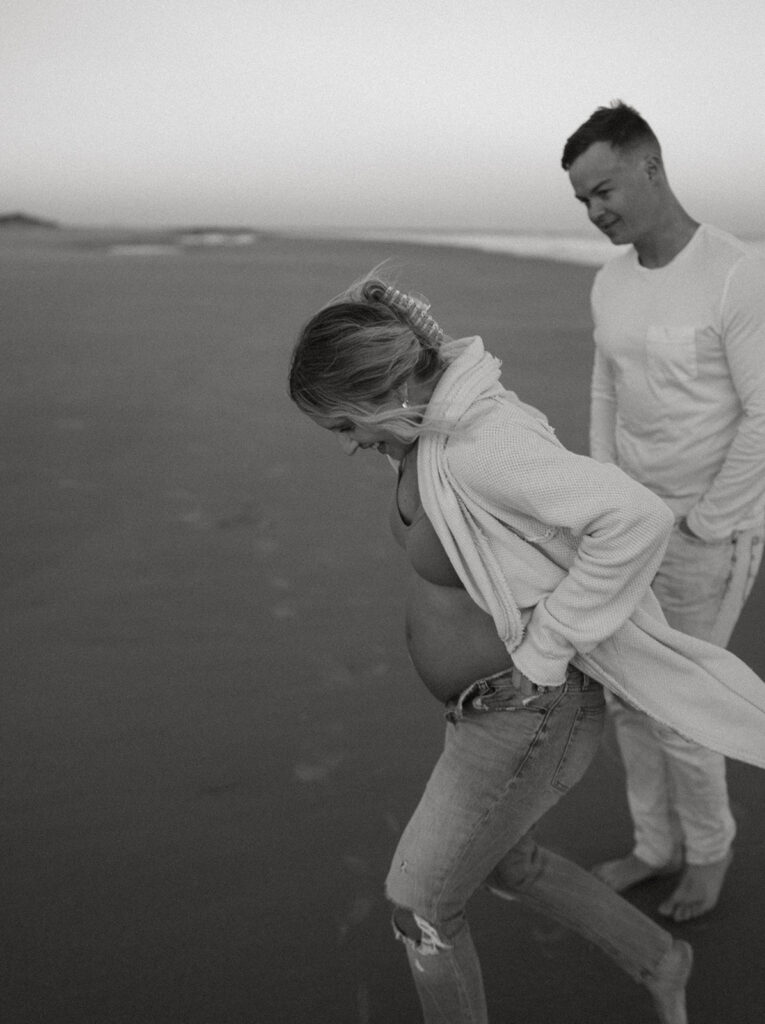 Couple running on the beach during maternity shoot