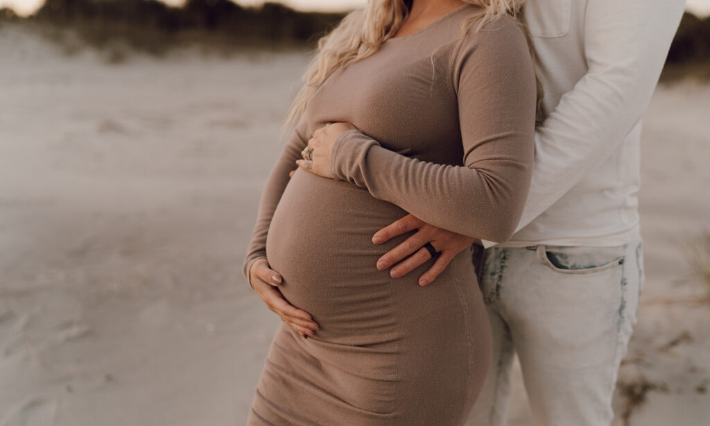 Couple holding baby bump during maternity shoot