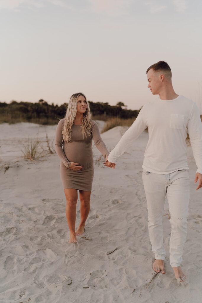 Couple walking on the beach during maternity shoot 