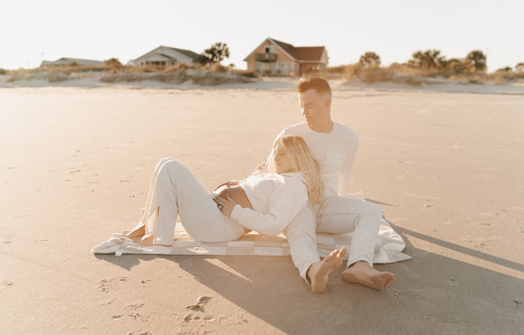 Couple laying on the beach during maternity shoot