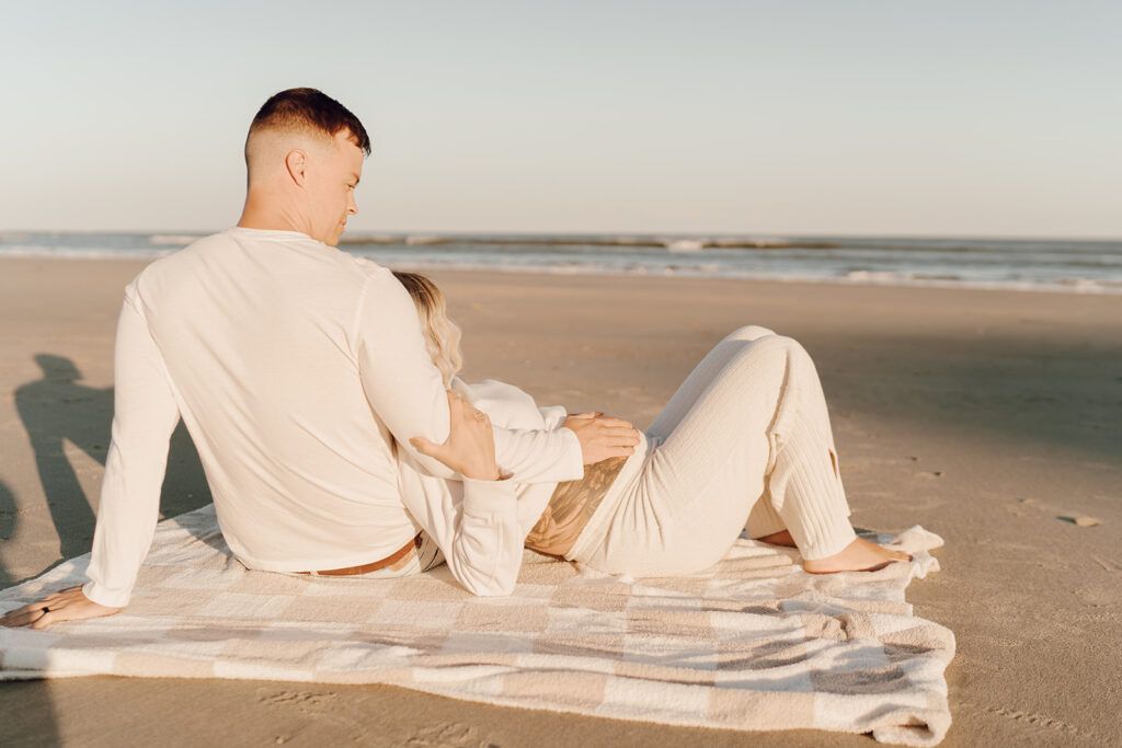 Couple laying on the beach during maternity shoot