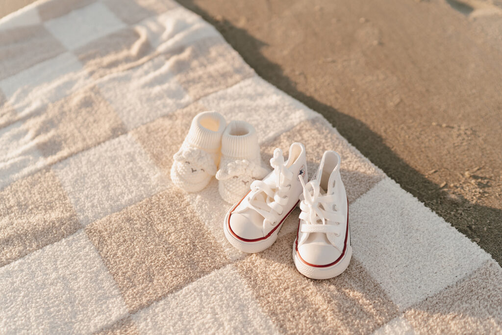 Baby shoes and socks on beach blanket at maternity shoot