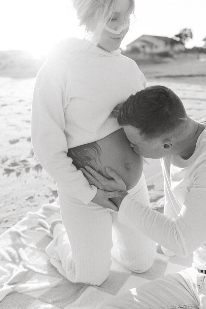 Couple kissing baby bump during maternity shoot