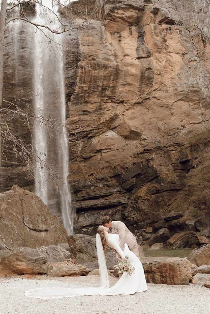 bride and groom kissing under toccoa falls waterfall