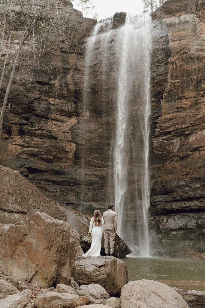 bride and groom standing under waterfall for destination elopement