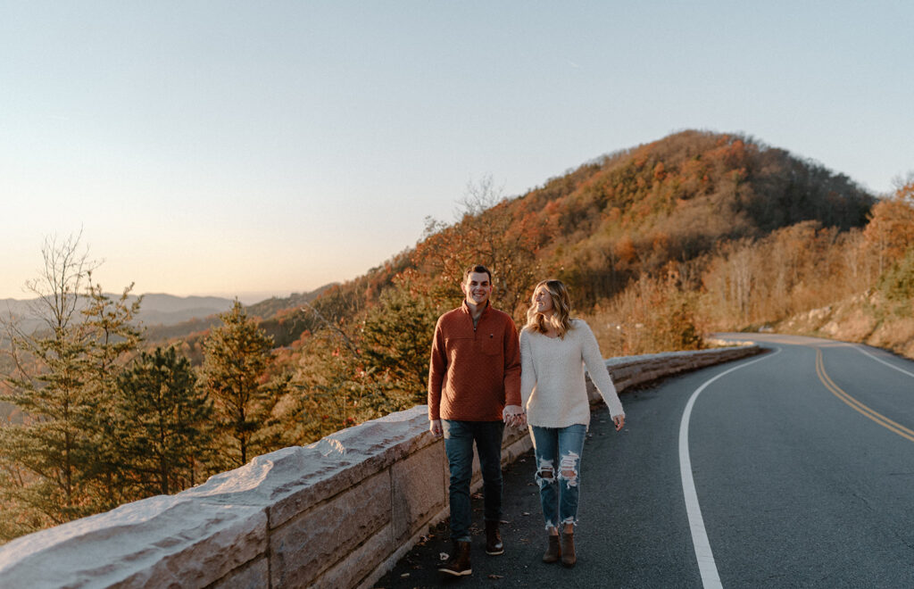 couple holding hands and walking on the bridge in front of mountains