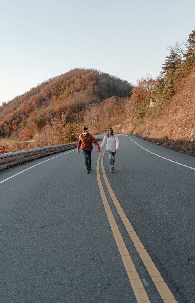 couple holding hands and running in front of the great smoky mountains