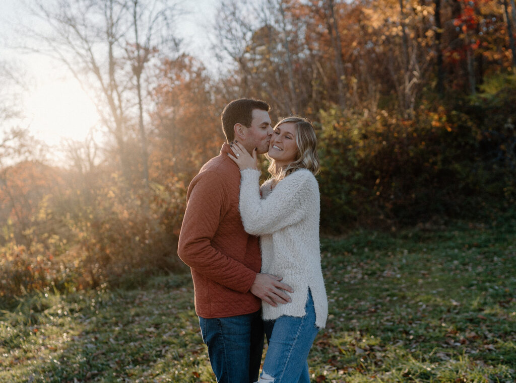 couple kissing in front of fall leaves