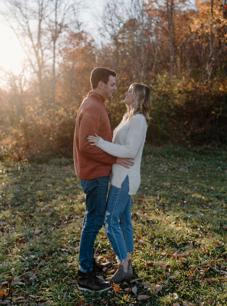 couple holding each other in front of fall foliage