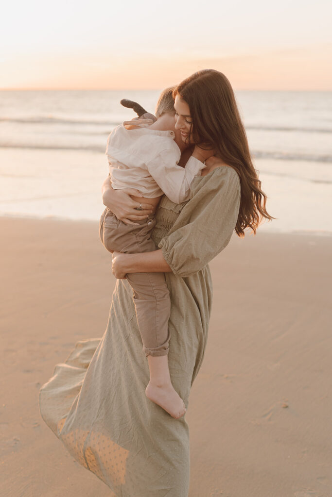 mom holding son and smiling on the beach