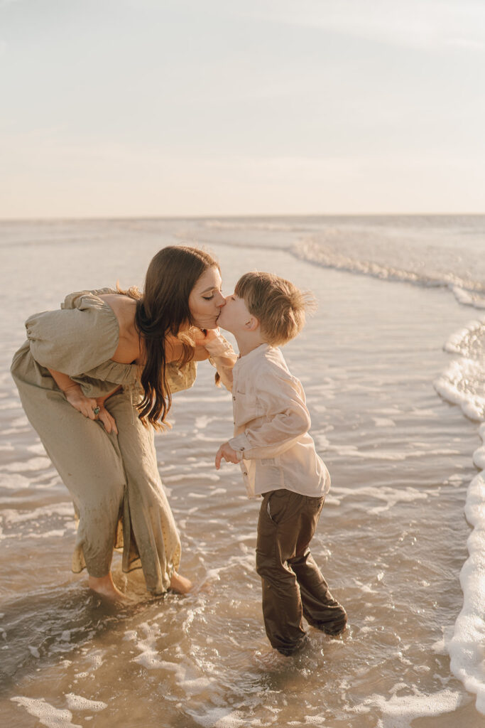 mom kissing son on the beach for beach family pictures