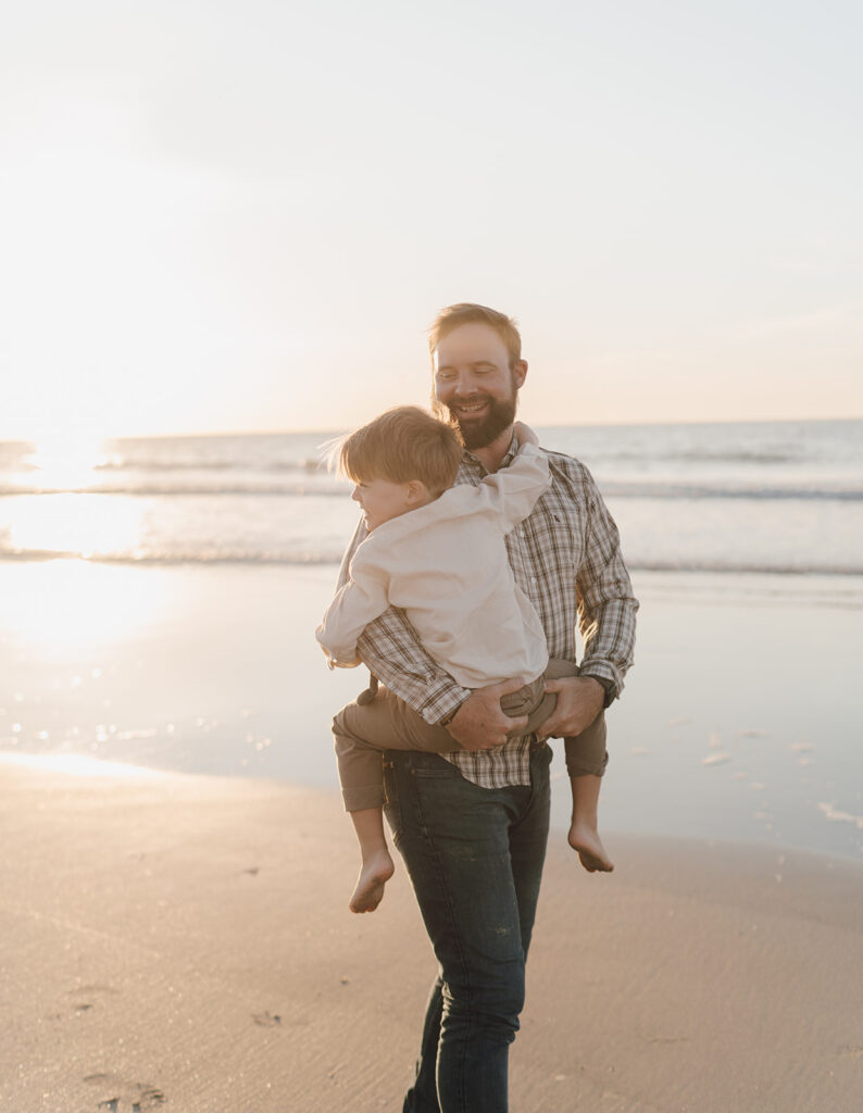 dad holding son and walking on the beach