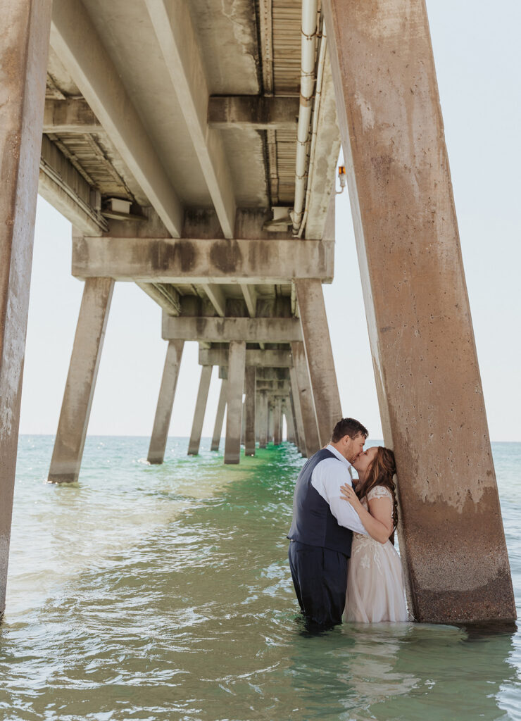 couple kissing under a bridge for wedding photos