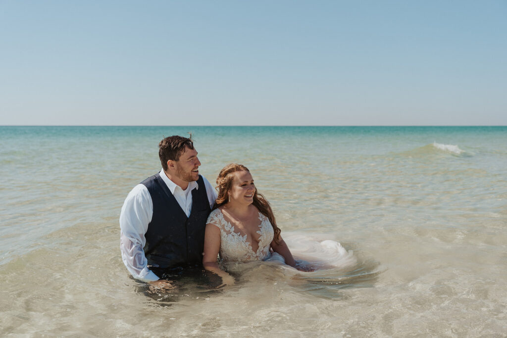 couple sitting in the water for bride and groom portraits