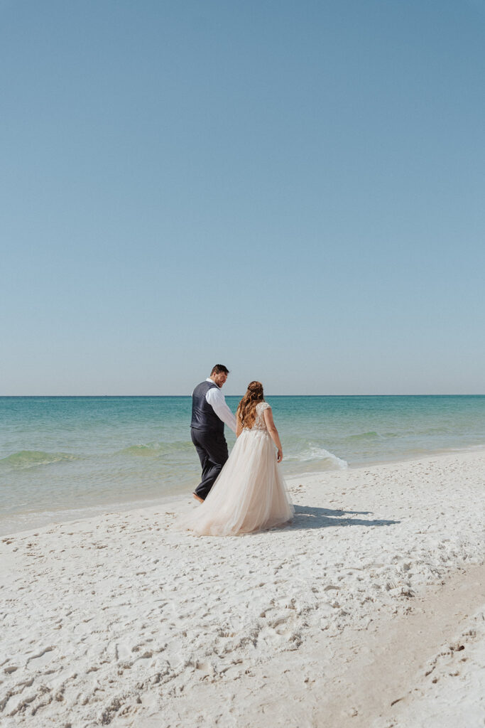 bride and groom walking on the shoreline of a destin beach