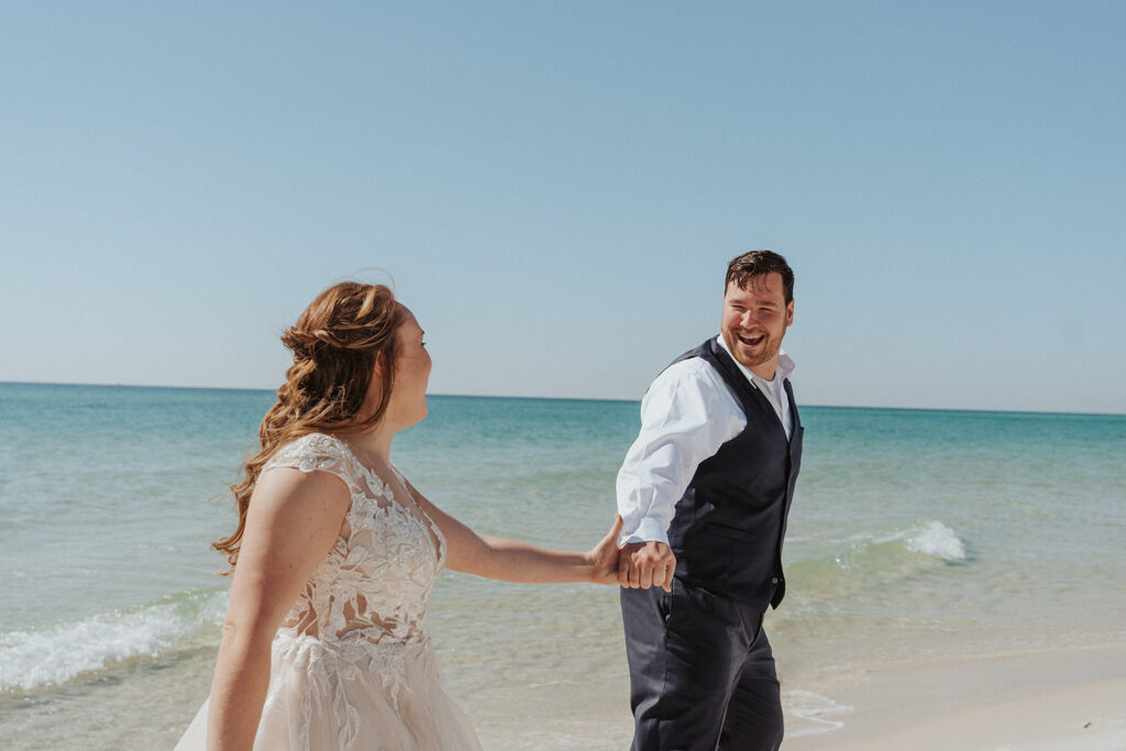 bride and groom smiling and laughing on the beach