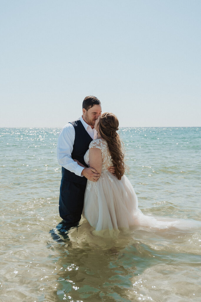 bride and groom kissing in the ocean
