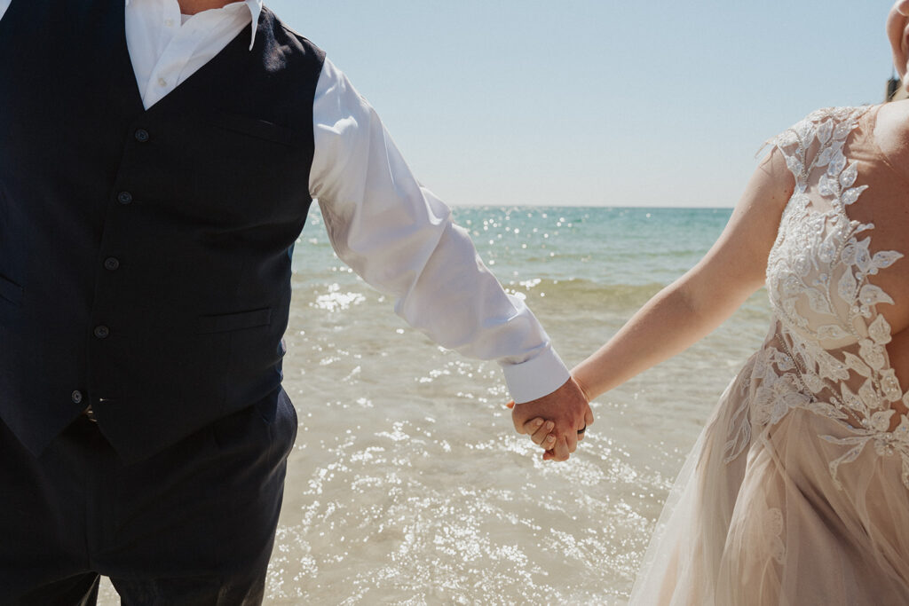 couple holding hands for wedding photos on the beach