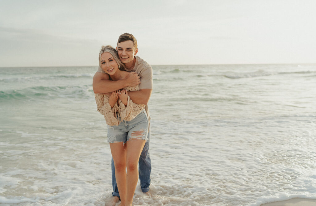 couple smiling and hugging during engagement photos on the beach