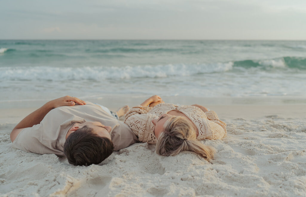 couple laying on the beach during engagement session in florida 30A photographer