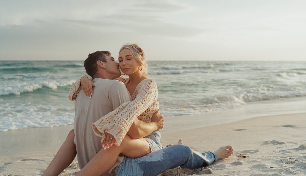 couple kissing and posing on the beach during engagement photoshoot