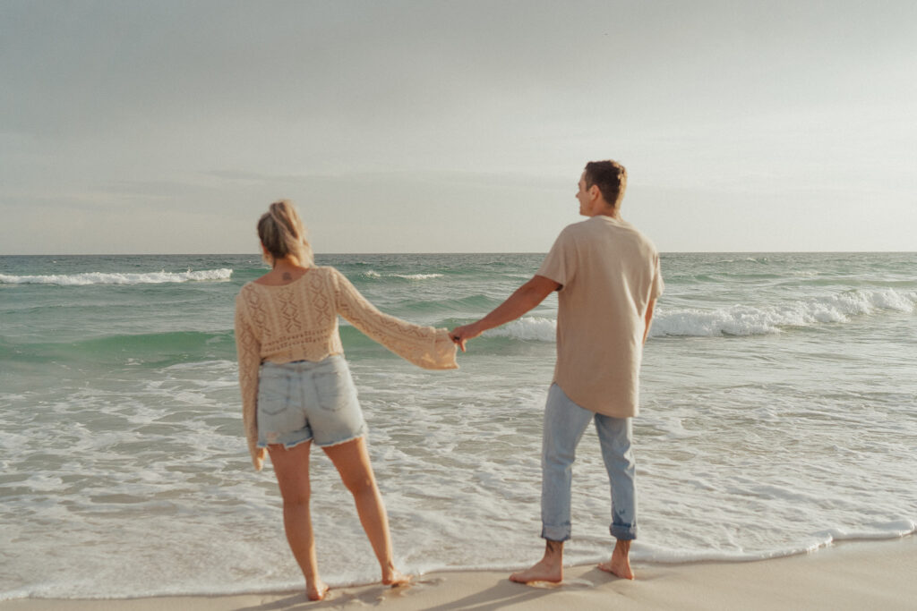couple holding hands on the beach in florida