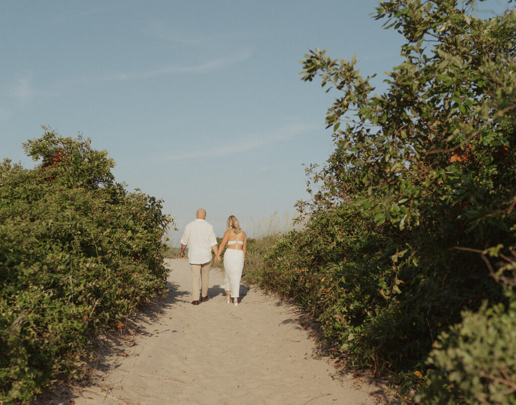 couple holding hands and walking away on the beach