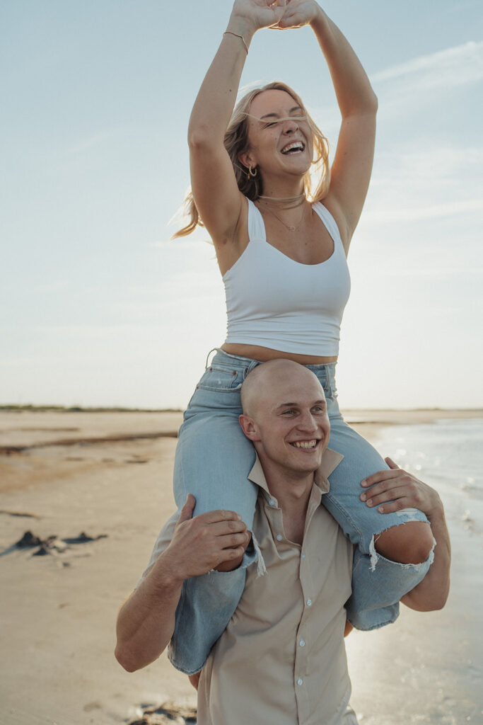 girl on guy's shoulders engagement session poses on the beach