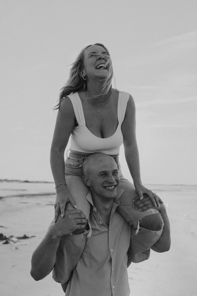 girl on guy's shoulders engagement session poses on the beach