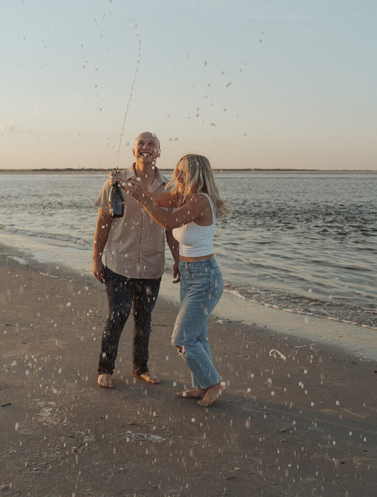 candid champagne pop engagement session on the beach