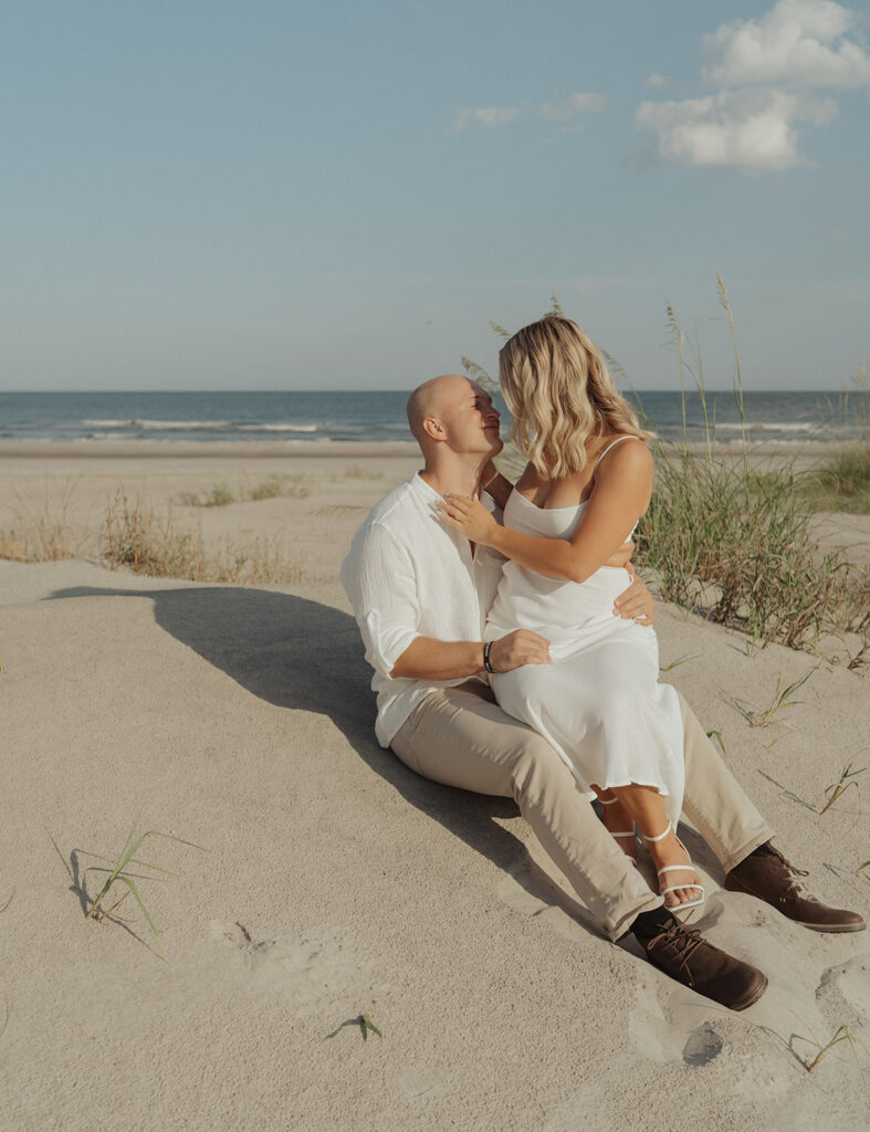 couple kissing pose for engagement session on the beach