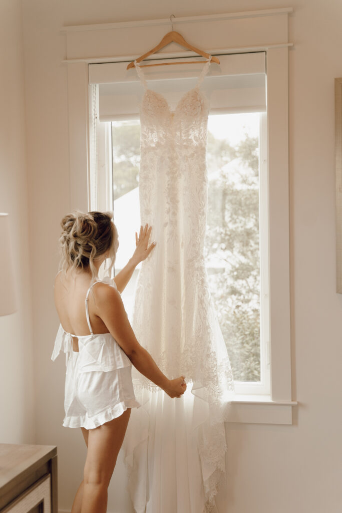 bride looking at wedding dress hanging up