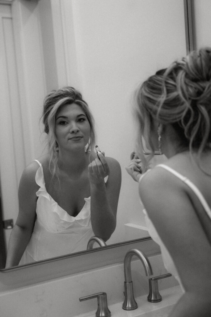 bride putting lipstick on in the mirror