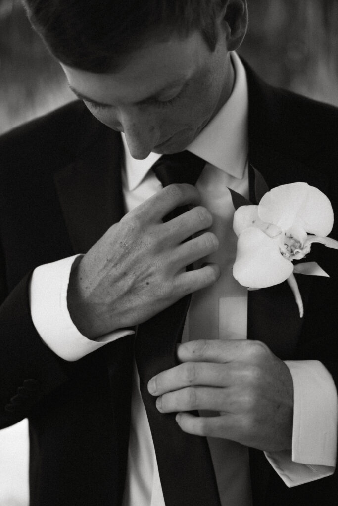 close up photo of groom fixing his tie