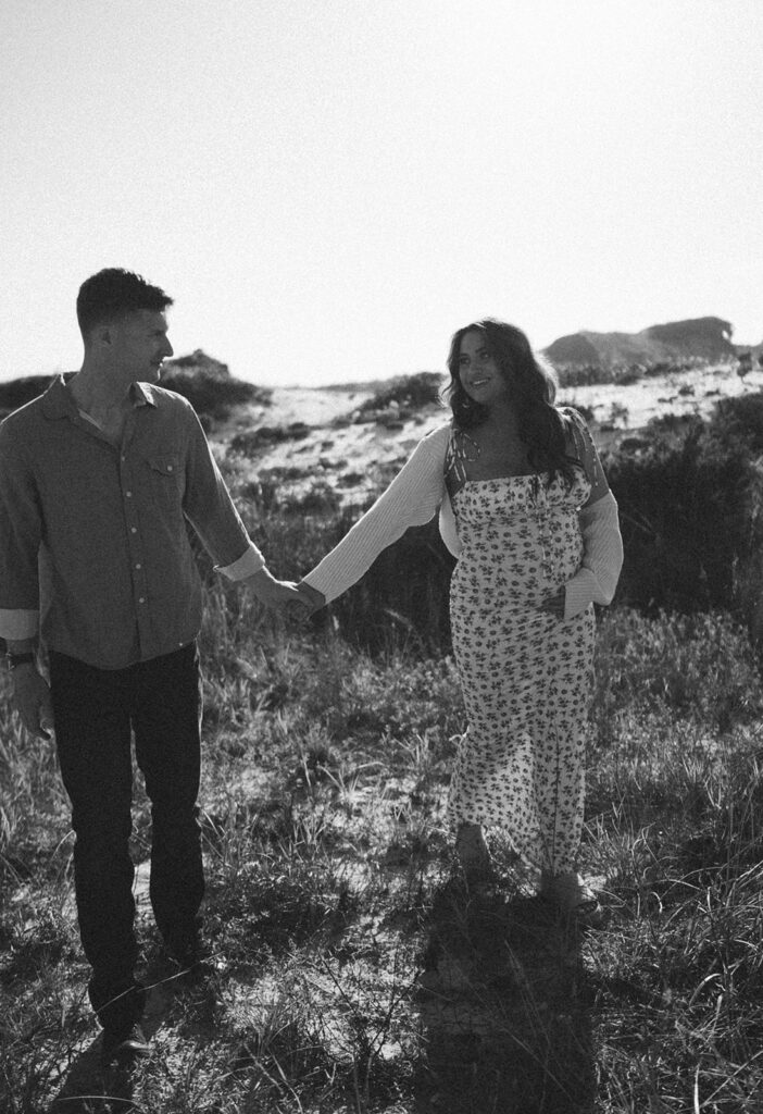 couple holding hands and smiling during Grayton Beach Maternity Photoshoot