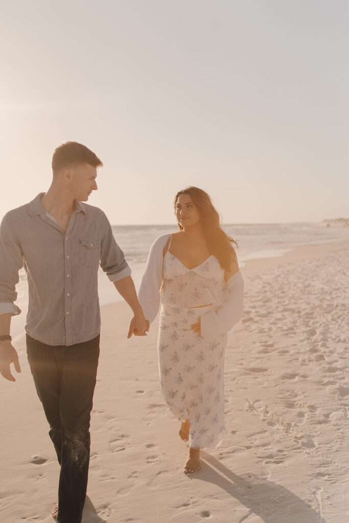 couple holding hands and walking on the beach