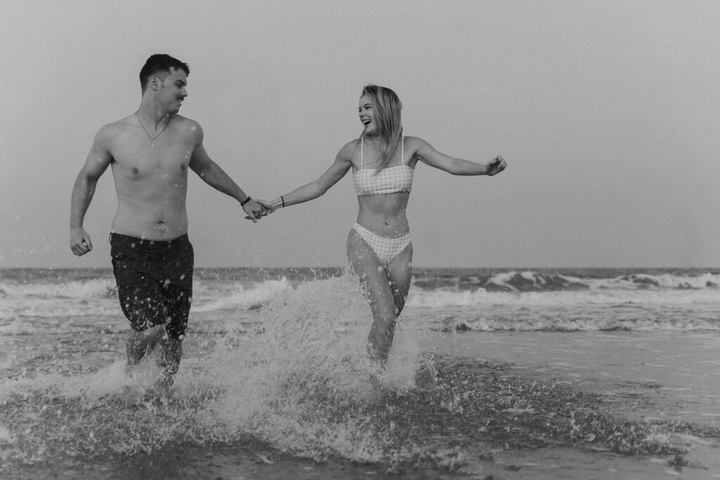 couple holding hands and splashing in the water