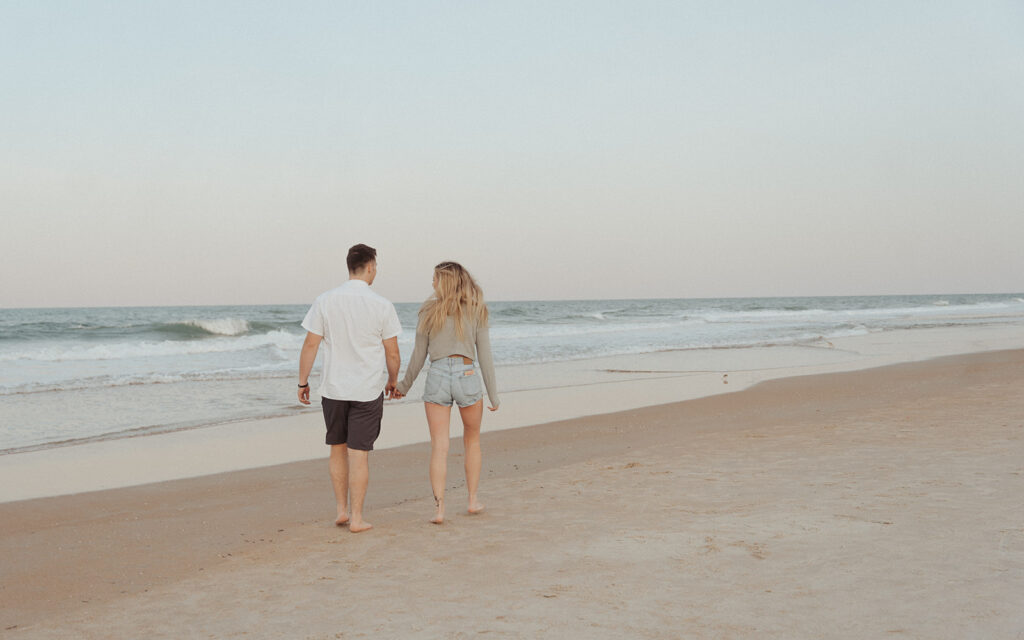 couple holding hands and walking on the beach