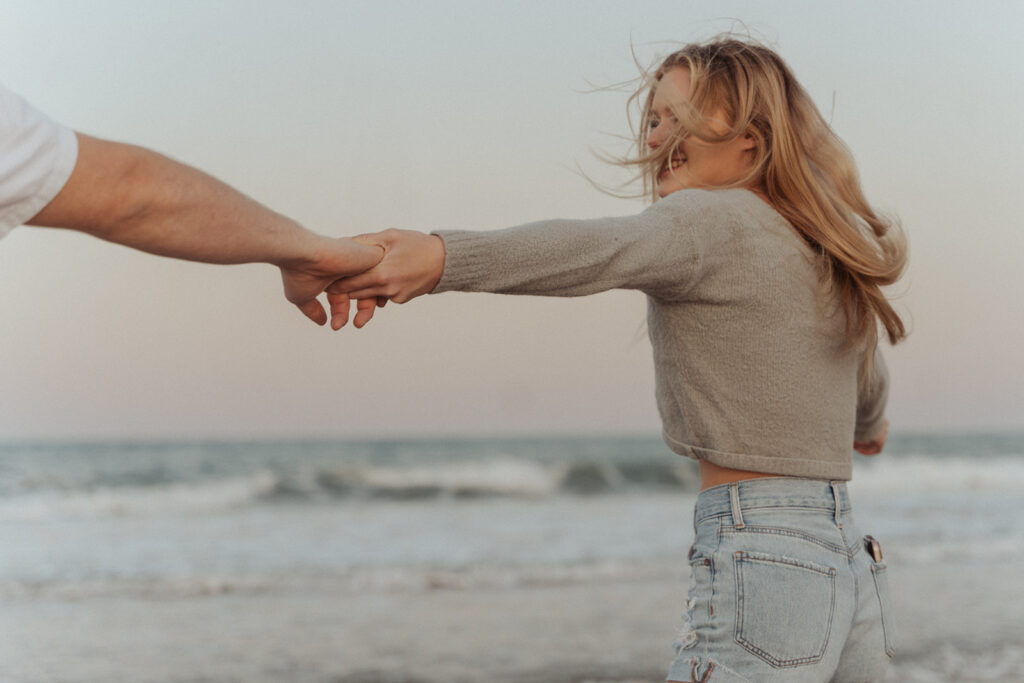 couple holding hands for beach engagement photos