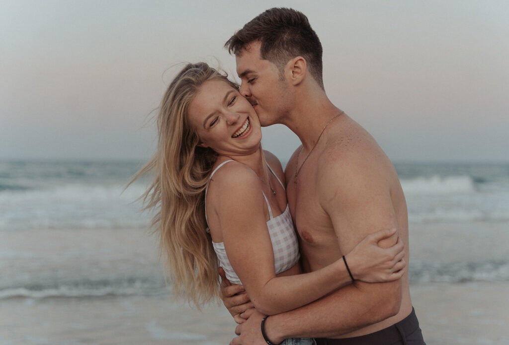 couple smiling and kissing on the beach during daytona couple session