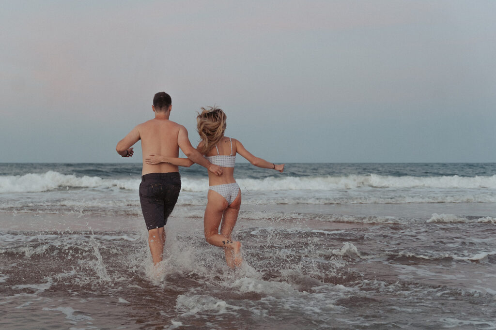 couple holding hands and splashing in the water