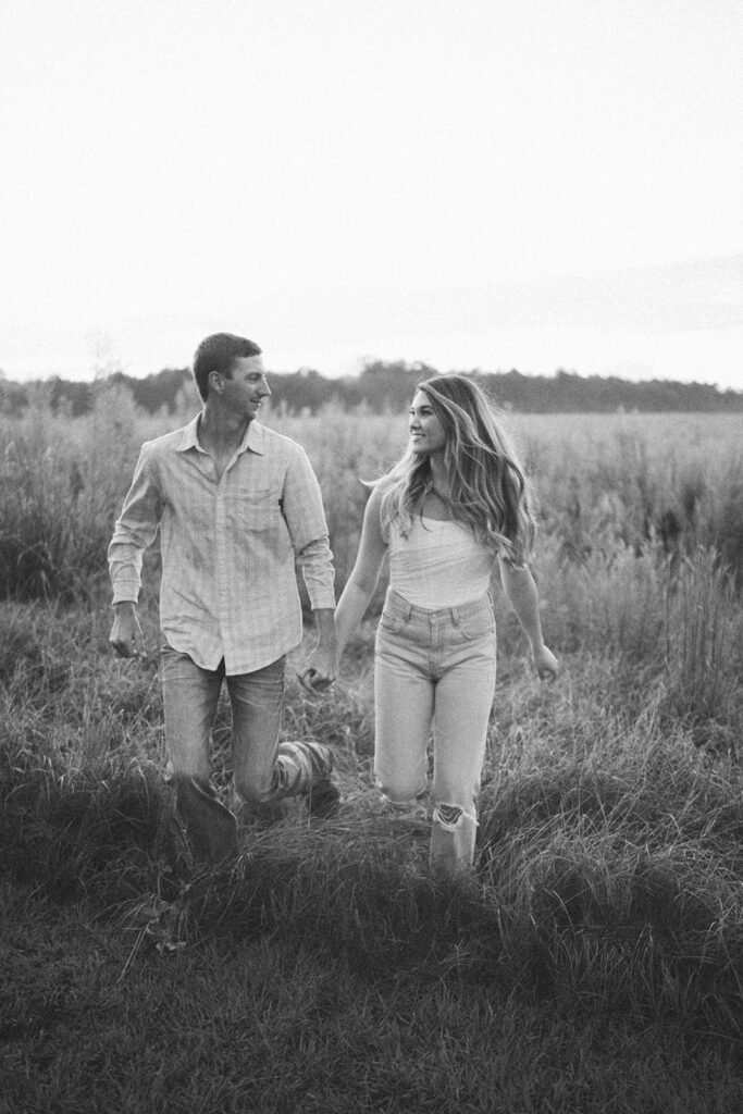 couple holding hands and walking in field